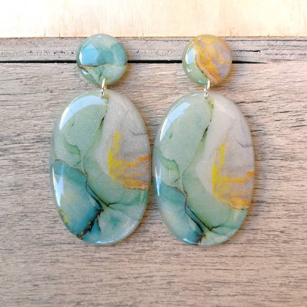 Oval earrings in pearly resin, with a teal-yellow pattern, which reproduces quartz. Length 6 cm, stainless steel closure.