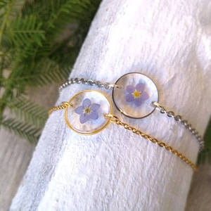 Women&#39;s bracelet with thin chain in stainless steel, with transparent resin pendant and Forget-me-not flower inserted. Ø 1.5 cm.