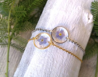 Women's thin chain bracelet in stainless steel, with transparent resin pendant and forget-me-not flower inserted. diameter 1.5cm.