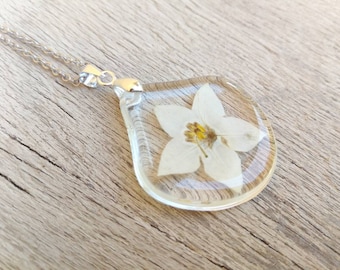 Drop pendant in transparent resin, with real jasmine flower inserted. Pendant L3.1xH3.2 cm. Thin stainless steel chain.