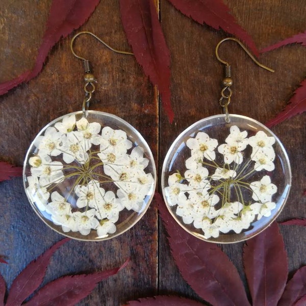Orecchini in resina trasparente con fiori bianchi di spirea. Chiusura a monachella. Diametro 3,8 cm, H 5,5 cm.
