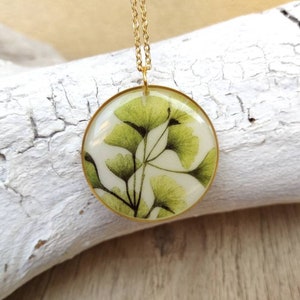 White resin pendant with leaf design. Thin brass hoop. Diameter 3 cm, thickness 5 mm. Gold colored stainless steel chain