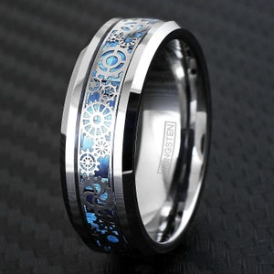 May include: A silver tungsten ring with a blue and silver gear design. The ring is engraved with the word "TUNGSTEN".