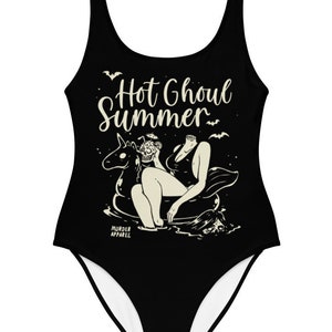May include: Black one-piece swimsuit with a white graphic of a skeleton riding a unicorn float. The text "Hot Ghoul Summer" is printed on the swimsuit.