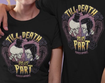 May include: A couple wearing matching black t-shirts with a graphic of two skeletons in a wedding pose. The text on the shirts reads "Till Death Do Us Part" with a gothic font and a skull and crossbones logo.