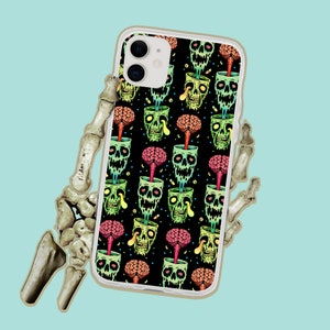 May include: A white iPhone case with a colorful pattern of green skulls and brains. The skulls are surrounded by a colorful design of flowers and leaves.