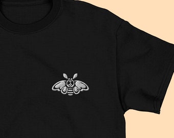 May include: Black t-shirt with a white embroidered moth design.