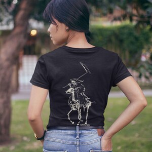 May include: Black t-shirt featuring a white graphic of a skeleton riding a skeletal horse and holding a scythe. The text "PREMIER APPAREL" is printed at the bottom of the graphic.