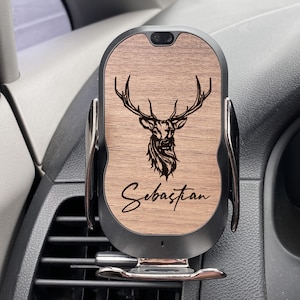 May include: A black and wood car phone charger with a deer silhouette and the name "Sebastian" engraved on it. The charger is mounted in a car's air vent.