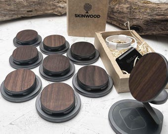 May include: A set of ten wireless charging pads with a wood veneer top. The pads are arranged in a circle with a larger charging pad in the center. The charging pads are all black and have a silver ring around the edge. The charging pads are all on a white surface. The image also shows a box with the logo "SKINWOOD" printed on it.