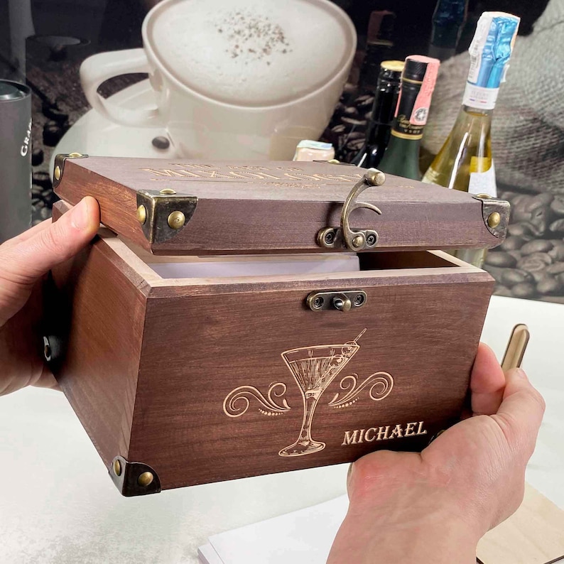 May include: A wooden box with a hinged lid and a brass latch. The box is engraved with a martini glass and the name "MICHAEL".