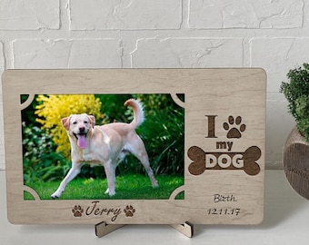May include: Wooden photo frame with a cutout of a bone and paw print. The text "I love my DOG" is engraved on the frame. A photo of a dog is in the frame. The dog's name "Jerry" and birthdate "12.11.17" are engraved below the photo.