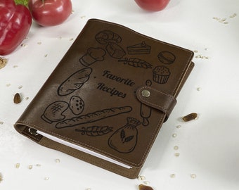 May include: Brown leather recipe journal with a black engraved design of various food items and the text "Favorite Recipes".