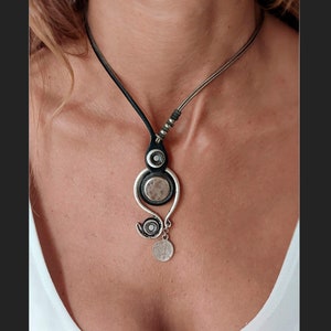 Pu&ograve; includere: Una collana argento e nera con un ciondolo unico che presenta pi&ugrave; cerchi e un ciondolo pendente. Il ciondolo &egrave; in metallo e ha una finitura testurizzata.