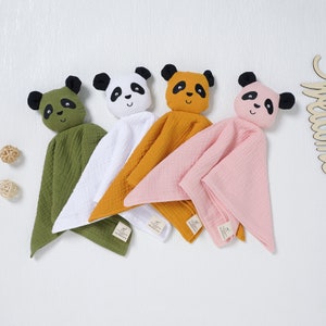 Peut inclure: Quatre peluches de panda pour bébé avec des couvertures attachées. Les pandas sont vert, blanc, orange et rose. Chaque panda a des yeux noirs et un nez noir.