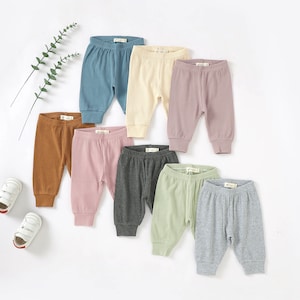 May include: Set of ten ribbed baby pants in various colors, including brown, pink, gray, green, and blue.