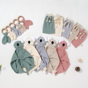 Puede incluir: Seis juguetes de peluche de koala para bebés con mantas de diferentes colores y bolsas de cordón a juego. Los juguetes están hechos de tela suave y texturizada y tienen caras bordadas. Las bolsas están hechas de una tela similar y tienen un cierre de cordón.