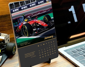 May include: A desk calendar for January featuring a red Ferrari Formula 1 race car driven by Lewis Hamilton on a track. The calendar displays the month, a grid of dates, and a quote by Murray Walker. The design includes black and red accents.