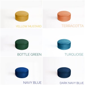 May include: A collection of six small, round velvet ottomans in various colors. Colors include yellow mustard, terracotta, bottle green, turquoise, navy blue, and dark navy blue. Each ottoman is labeled with its respective color name.