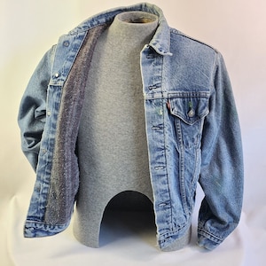 May include: A blue denim jacket with a fleece lining. The jacket has a button closure and two front pockets.