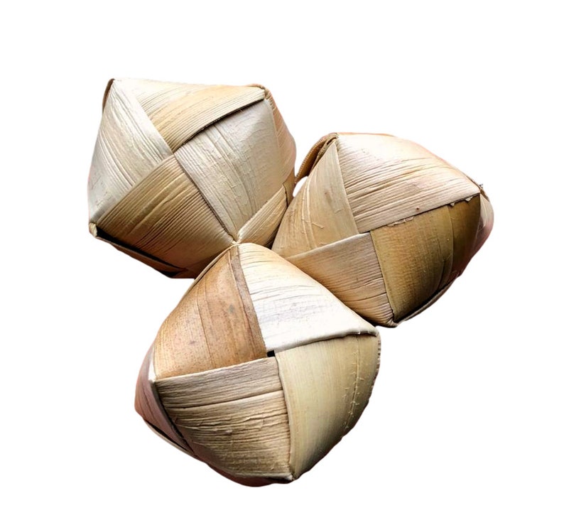 May include: Three woven palm leaf spheres, each with a geometric, diamond-like pattern. The natural, light brown color of the leaves creates a rustic, earthy aesthetic. The spheres are arranged in a triangular cluster against a white background.