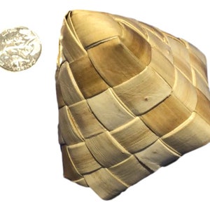May include: A woven basket with a square shape, crafted from light and dark brown natural fibers. The basket has a checkered pattern. A silver coin is next to the basket.