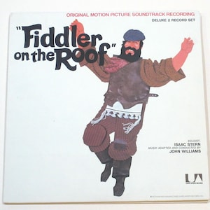 May include: A vintage "Fiddler on the Roof" Deluxe 2 Record Set album cover. The cover features a cartoon illustration of a man in traditional attire with arms raised. Text includes the title, soloist, and music credits.