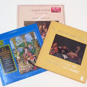 May include: Three vinyl records with colorful covers. The first record is blue with a medieval scene of a man and woman playing music in a garden. The second record is beige with a picture of a lute and a violin. The third record is yellow with a picture of a man playing a lute. The text on the covers reads "In a Medieval Garden", "The Julian Bream Consort", and "An Evening of Elizabethan Music".