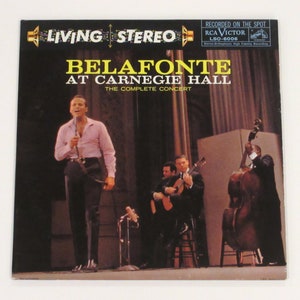 May include: A vintage record album cover featuring a black and white photo of a man singing on stage with a band. The album cover is titled "Belafonte at Carnegie Hall: The Complete Concert" and features the RCA Victor logo.