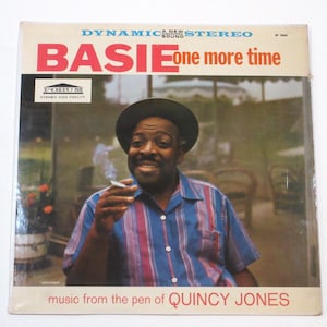 May include: A vintage vinyl record album cover featuring a portrait of a man wearing a hat and a striped shirt. The album title is "BASIE one more time" and the text "music from the pen of QUINCY JONES" is at the bottom of the cover.