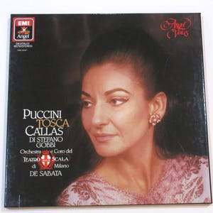 May include: A vintage vinyl record album cover featuring a portrait of a woman with dark hair and a pink dress. The album is titled "Puccini Tosca Callas" with the EMI and Angel Records logos.