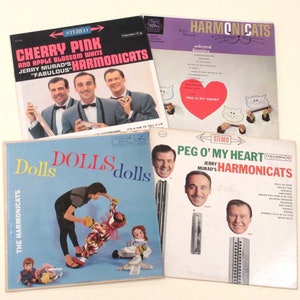 May include: Four vintage vinyl records featuring Jerry Murad's Harmoncats. The records are titled "Cherry Pink and Apple Blossom White", "Peg O' My Heart", "Dolls", and "Harmoncats - Selected Favorites".