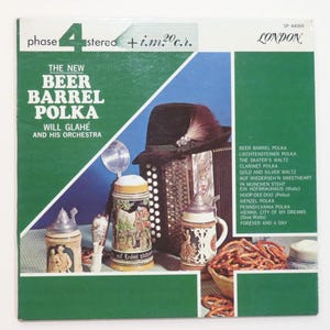 May include: A vintage vinyl record cover for The New Beer Barrel Polka by Will Glahé and His Orchestra. The cover features a dark hat, an accordion, three ceramic beer steins, and a basket of pretzels against a green and blue background.