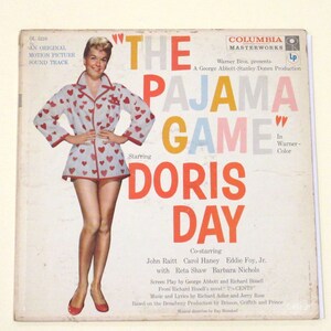 May include: A vintage Columbia Masterworks LP record cover featuring Doris Day in a white and red heart-patterned pyjama top and red shoes. The title of the record is "The Pajama Game" in large, colourful letters. The cover also includes the names of the co-stars, John Raitt, Carol Haney, Eddie Foy Jr., Reta Shaw, and Barbara Nichols.