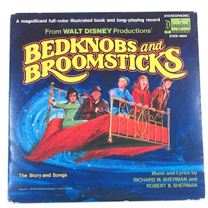 May include: A vintage record album cover featuring a colorful illustration of a bed flying through the air with a group of children on it. The album is titled "Bedknobs and Broomsticks" and is from Walt Disney Productions. The album cover is in a blue, red, and yellow color scheme.