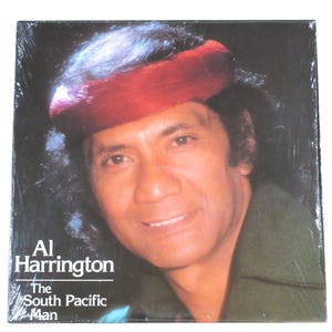 May include: A vinyl record cover featuring a man with a red headband and a green shirt. The text on the cover reads "Al Harrington The South Pacific Man".