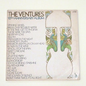 May include: A vintage vinyl record album cover featuring a light brown background with a floral design. The album is titled "The Ventures 10th Anniversary Album" and lists the songs included on the record: "Spinning Wheel", "Bridge Over Troubled Water", "By The Time I Get To Phoenix", "Those Were The Days", "Never My Love", "Dellah", "Strangers In The Night", "Everybody's Talkin", "Raindrops Keep Fallin' On My Head", "Blowin' In The Wind", "Who'll Stop The Rain", "Sweet Caroline", "Let It Be", "Up-Up And Away", "Bad Moon Rising", "Eleanor Rigby", "Good Morning Starshine", "MacArthur Park", "Hey Jude", "Michelle", "Sugar, Sugar", "The Sounds Of Silence", and "Don't Think Twice, It's All Right".