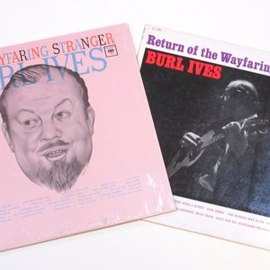 May include: Two vinyl record albums by Burl Ives. The first album is titled "The Wayfaring Stranger" and features a cartoon illustration of Burl Ives on a pink background. The second album is titled "Return of the Wayfaring Stranger" and features a black and white photo of Burl Ives playing a guitar.