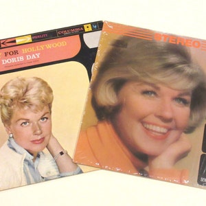 May include: Two vintage vinyl records featuring Doris Day. The first record is titled "Hooray for Hollywood" and the second is titled "Doris Day Sings Her Great Movie Hits". Both records feature a photo of Doris Day on the cover.