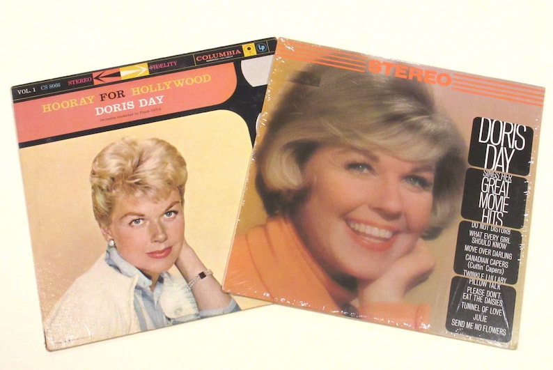 May include: Two vintage vinyl records featuring Doris Day. The first record is titled "Hooray for Hollywood" and the second is titled "Doris Day Sings Her Great Movie Hits". Both records feature a photo of Doris Day on the cover.