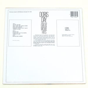 May include: White vinyl record album cover with a black and white photo of Doris Day. The album title is "Doris Day Sings Her Great Movie Hits". The album cover lists the songs on each side of the record.