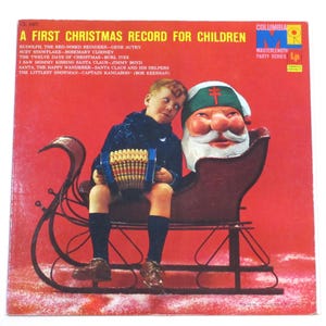 May include: Vintage Christmas record album cover with a red background. The album is titled "A First Christmas Record for Children." A young person sits in a Santa sleigh next to a Santa Claus head. The person holds an accordion.