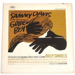 May include: A vintage record album cover featuring a black and white illustration of two hands reaching towards each other. The album is for the musical "Golden Boy" starring Sammy Davis Jr. and Billy Daniels. The text on the cover reads "Hilliard Elkins Presents Sammy Davis Jr. in the New Musical Golden Boy. Original Broadway Cast. Clifford Odets & William Gibson - Music by Charles Strouse - Lyrics by Lee Adams. Billy Daniels. Directed by Arthur Penn."