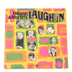 May include: A yellow, orange, pink, and green record album cover with the text "Rowan & Martin's Laugh-In" in black letters. The cover features photos of various cast members from the show, including Rowan Atkinson and Martin Short.
