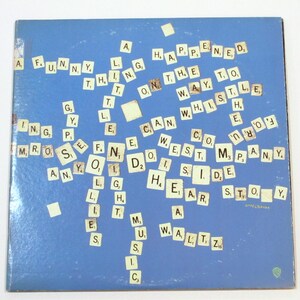 May include: A blue album cover with scattered Scrabble tiles spelling out phrases like "A Funny Thing Happened On The Way To The Forum." The album features the Warner Bros. logo and the artist's signature.