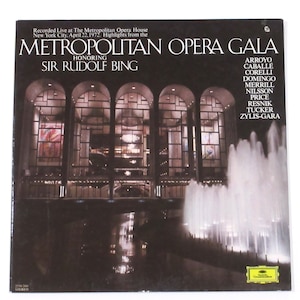 May include: A vintage record album cover featuring a black and white photo of the Metropolitan Opera House in New York City. The album title is "Metropolitan Opera Gala" honoring Sir Rudolf Bing. The album features a list of opera singers including: Arroyo, Caballe, Corelli, Domingo, Merrill, Nilsson, Price, Resnik, Tucker, and Zylis-Gara.