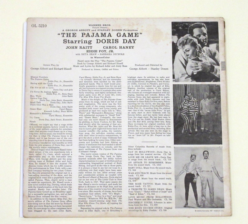 May include: A black and white photograph of Doris Day and Eddie Foy Jr. from the musical "The Pajama Game". The photo is from the back cover of a Warner Bros. record album. The album cover also includes the title of the musical, the names of the stars, and the names of the producers.