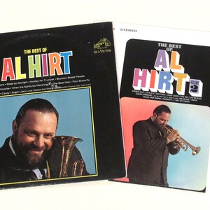 May include: Two vintage vinyl records featuring the musician Al Hirt. The album covers are black and white, with the text "The Best of Al Hirt" in bold, colorful lettering. One cover shows Hirt playing a trumpet, the other shows him with a brass instrument.