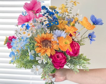 May include: A colorful bouquet of artificial flowers, including sunflowers, daisies, and roses in shades of pink, yellow, blue, and orange.