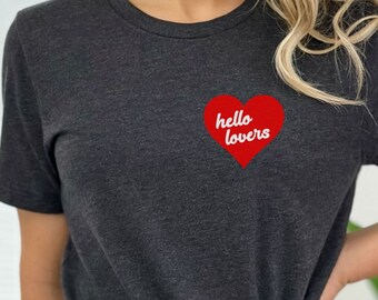 May include: A dark gray t-shirt with a red heart graphic that says "hello lovers" in white text.